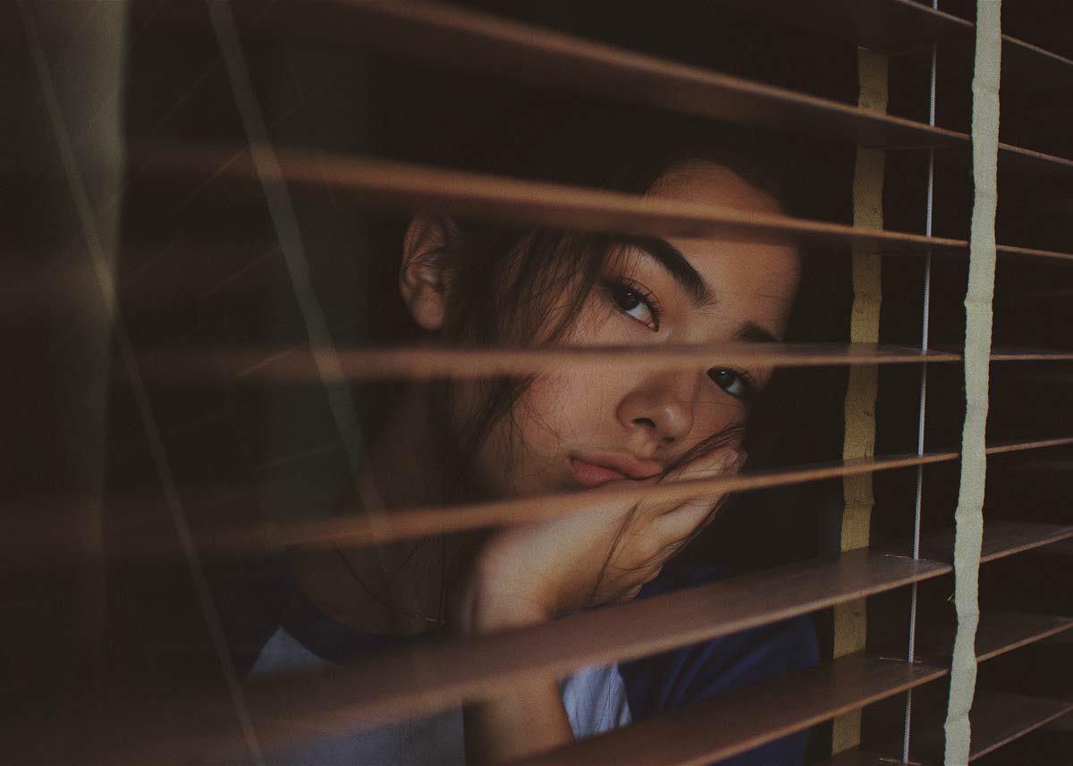 a young women looks through a window as she considers an abortion